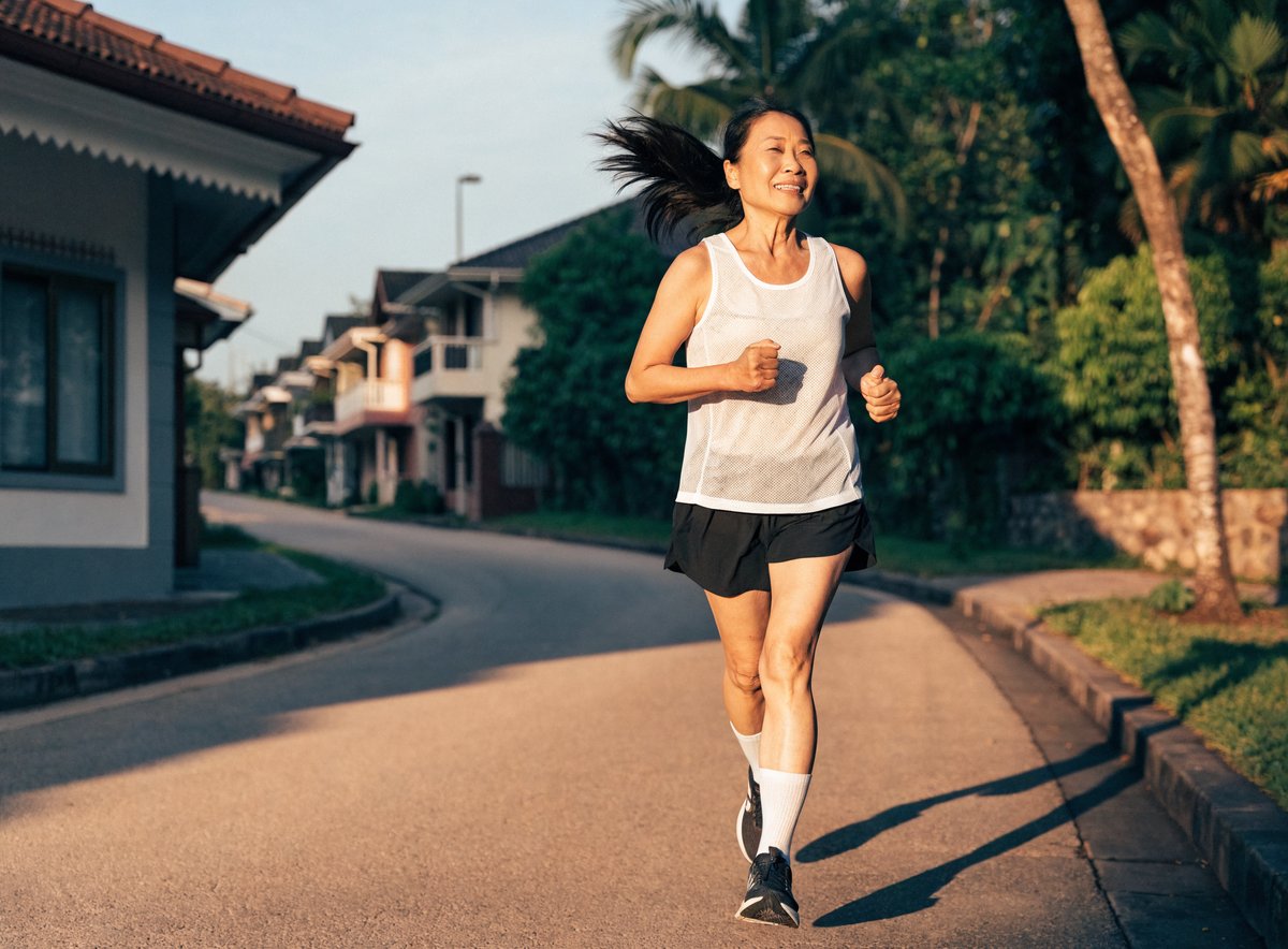 A healthy older woman jogging briskly along a quiet neighbourhood street in the morning