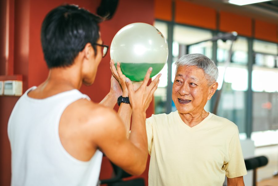 Isaiah Chng coaching a senior client through a balance exercise with a stability ball