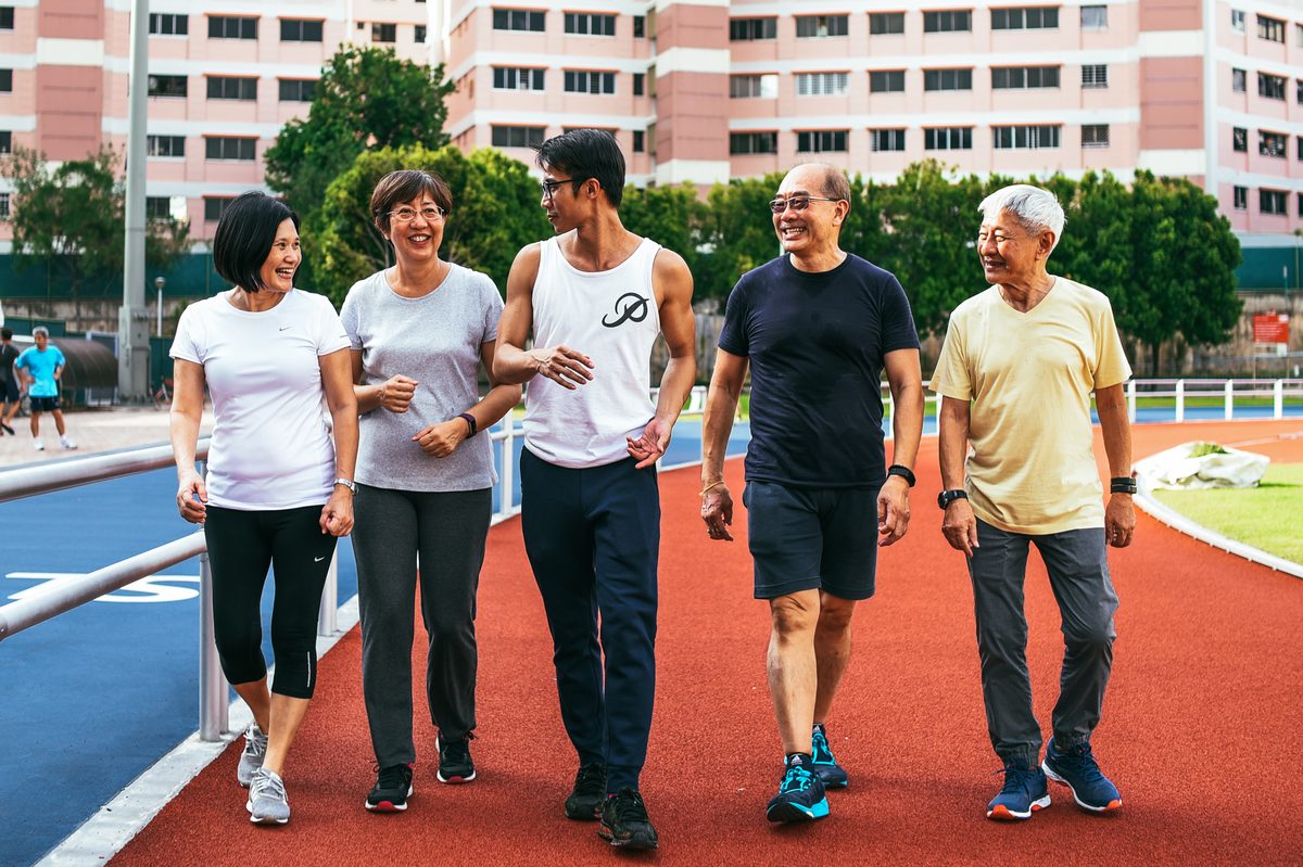 A group of ProAge participants walking together, smiling, at an outdoor track in Singapore
